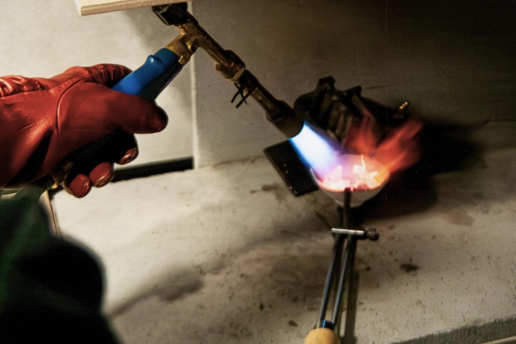 Topienie metalu podczas ręcznego tworzenia biżuterii w pracowni złotniczej